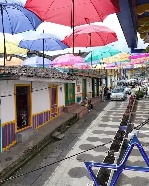 Calle decorada con sombrillas de colores en un pueblo de montaña